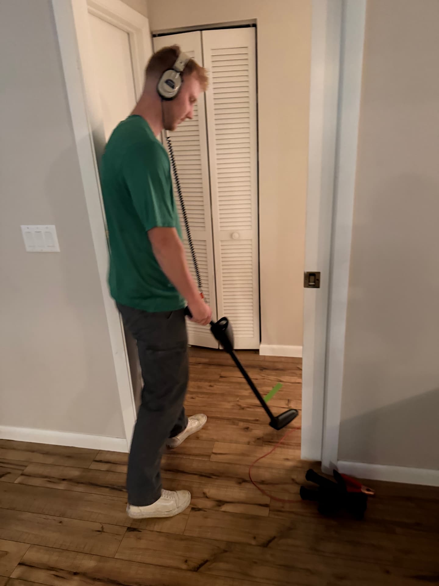 Technician using the Pulsar 2000 line tracer to follow a pipe under a wood floor
